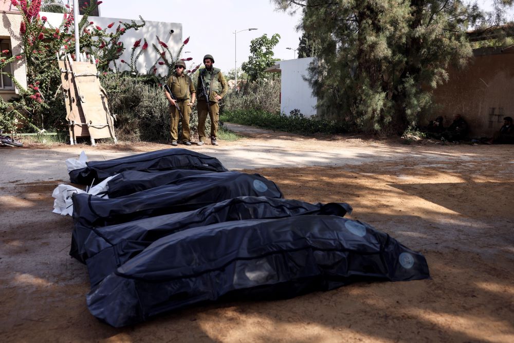 Israeli soldiers stand guard over bodies in Kfar Aza, a kibbutz in southern Israel, Oct. 10. The dead were victims of an Oct. 7 massacre carried out on the community by Hamas infiltrators.. (OSV News/Reuters/Ronen Zvulun)
