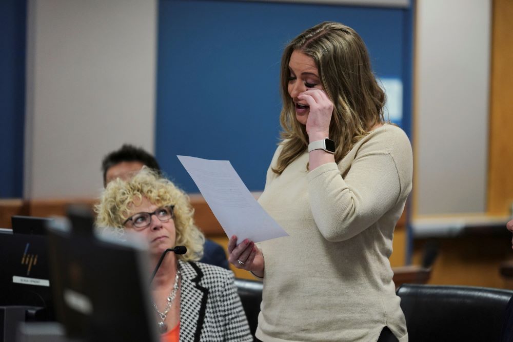 Jenna Ellis stands in courtroom while holding a piece of paper and wiping her eye. 