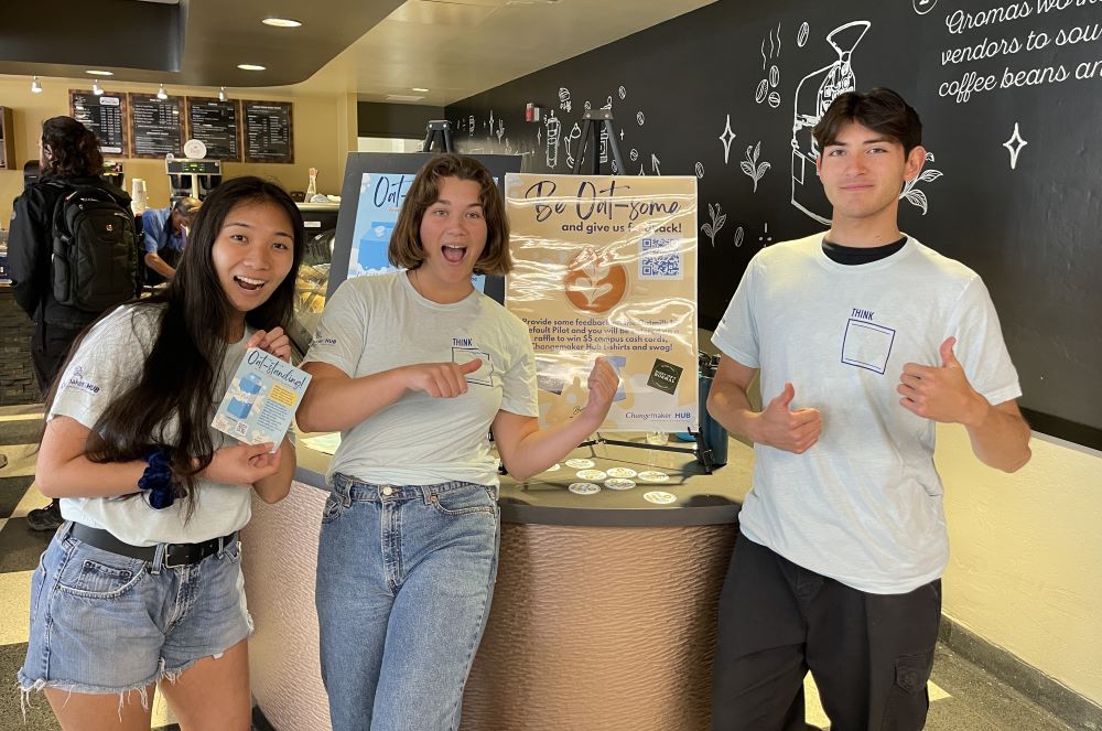 Three students active with University of San Diego’s Changemaker Hub, a partner of USD's Food Studies Initiative, pose at Aromas, a USD campus coffee shop, during April 2023's trial run of an oat milk default in drinks ordered at the café. (Courtesy of Aaron Gross)