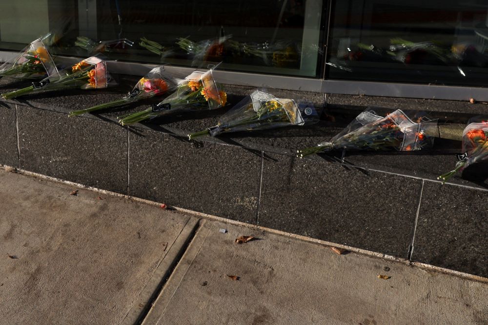 Bouquets of flowers lie on the ground at entrance of medical center.