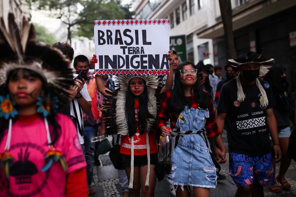 Indigenous people march with a sign that says "Brazil Indigenous Land" as they mark the International Day of the World's Indigenous Peoples in São Paulo Aug. 9, 2022.