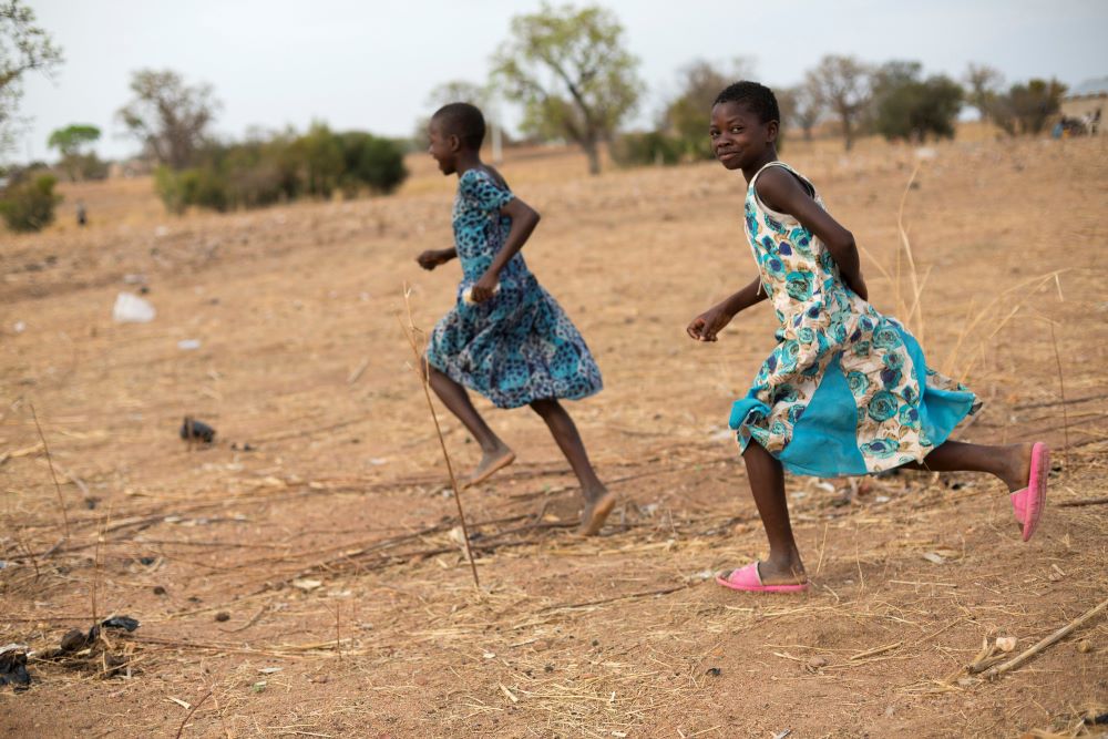 Children in Ghana run together through a dry field that has been severely affected by irregular weather patterns caused by climate change in this Oct. 4, 2022 file photo. 