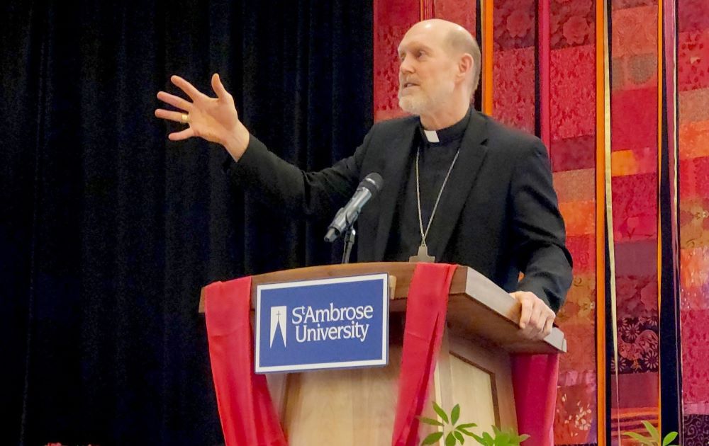 Bishop Thomas Zinkula stands, one hand outstretched, as he speaks at a lectern.
