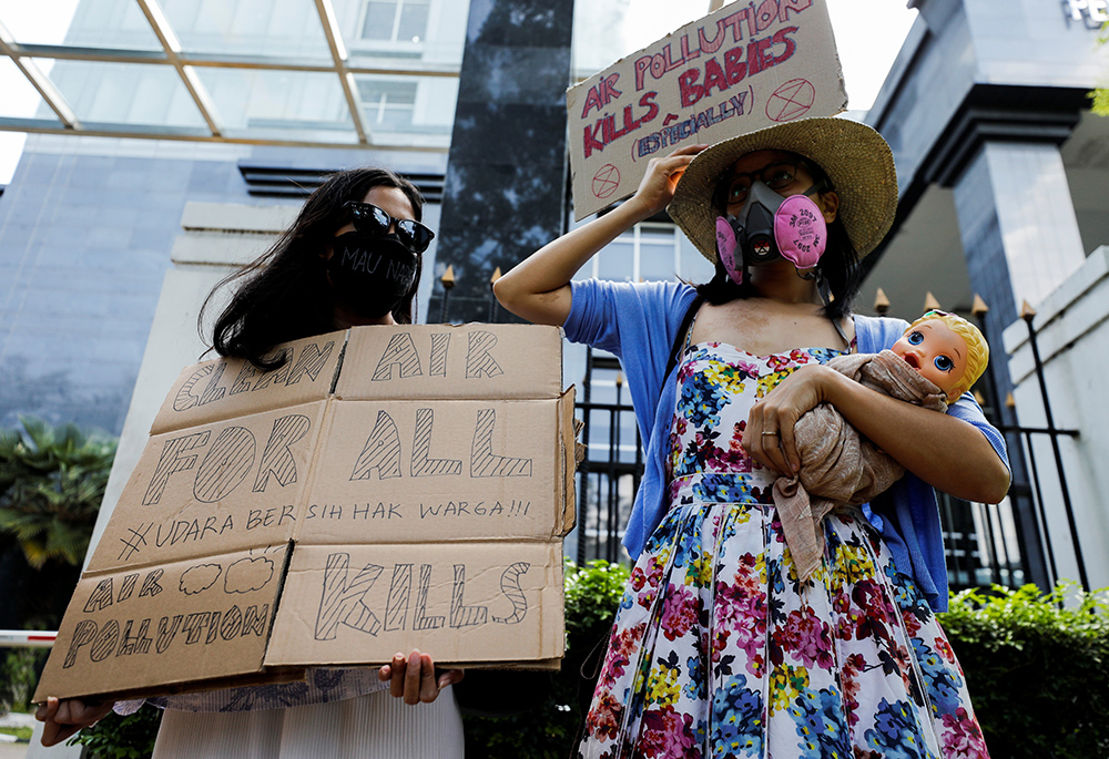 Environmental activists wearing protective masks hold placards outside the central court in Jakarta, Indonesia, Sept. 16, 2021, after citizens sued the government for the city's chronic levels of air pollution. Donna Haraway said that the Vatican does not talk enough about the devastating climate and environmental impacts on the unborn. (CNS/Reuters/Willy Kurniawan)