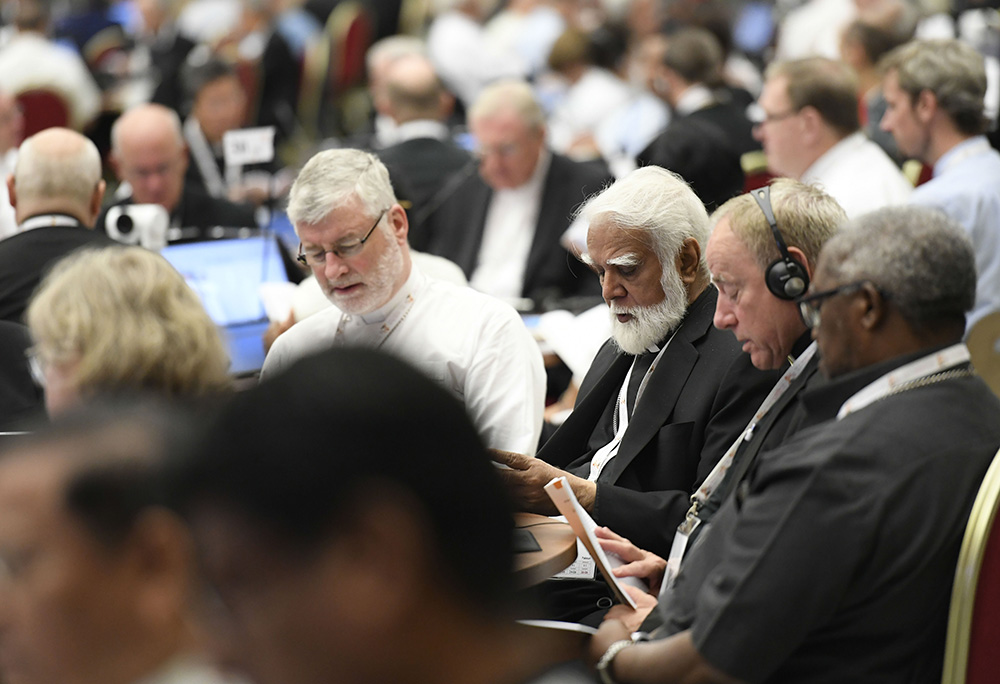 Bishop Shane Mackinlay of Sandhurst, Australia, left, an elected member of the Commission for the Synthesis Report of the assembly of the Synod of Bishops, recites morning prayer with Cardinal Joseph Coutts, retired archbishop of Karachi, Pakistan, center, and Archbishop Michael Miller of Vancouver Oct. 12 in the Paul VI Audience Hall at the Vatican. (CNS/Vatican Media)