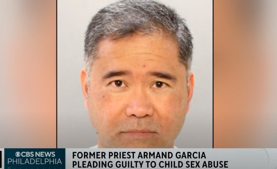 A brown man with graying black hair looks at the camera. A chiron at the bottom of the screen reads CBS News Philadelphia -- Former Priest Armand Garcia Pleading Guilty to Child Sex Abuse