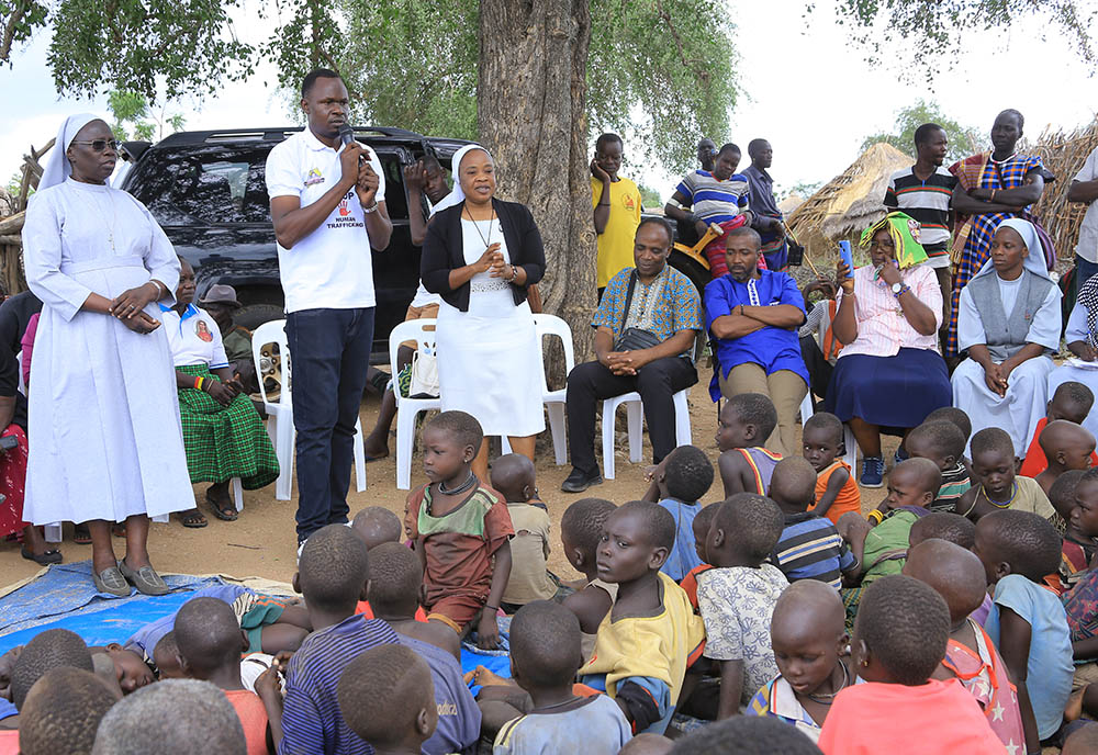 From left: Sr. Mary Lilly Driciru, a Missionary Sister of Mary Mother of the Church and coordinator of the Africa Faith and Justice Network women's empowerment program in Uganda; a translator; and Notre Dame de Namur Sr. Eucharia Madueke address a rural community in Karamoja, Uganda, about child trafficking to Kampala, Uganda. (Courtesy of Eucharia Madueke)