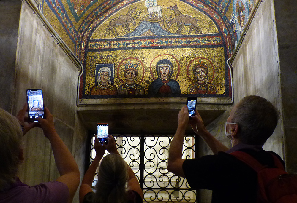 Participants in the Oct. 3 "Let Her Voice Carry" prayer vigil hosted by women's ordination advocates at Rome's Basilica of St. Praxedes take photos in the basilica's Chapel of St. Zeno. The mosaic pictured dates from the ninth century and contains, at far left, an image of Theodora, the mother of Pope Paschal I. The mosaic identifies her as "Theodora Episcopa." (NCR photo/Rhina Guidos)