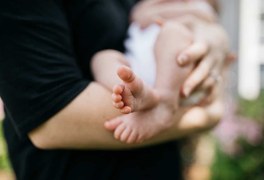Photo illustration of a woman holding a baby (Unsplash/Wes Hicks)