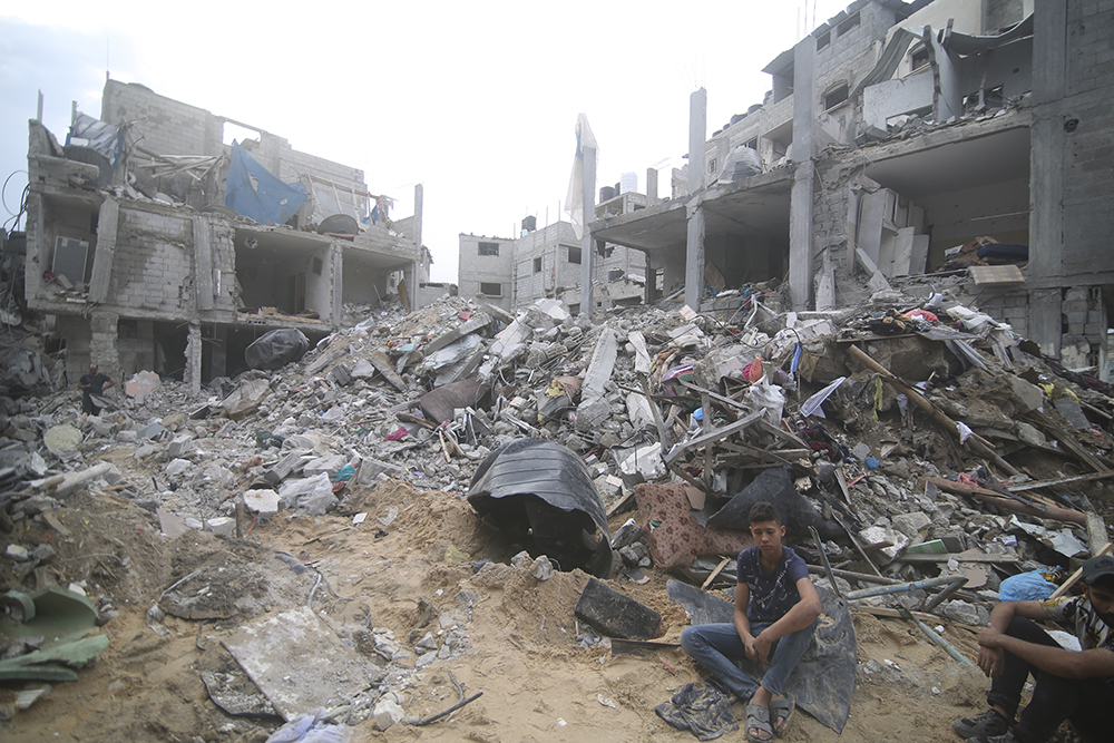 Palestinians sit by the rubble of the Abu Hilal family home in Rafah refugee camp, Gaza Strip, Oct. 9. The strike killed dozens of people. (AP/Hatem Ali)