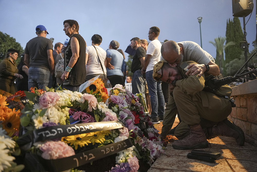 Friends and relatives of Ilai Bar Sade mourn next to his grave during his funeral at the military cemetery in Tel Aviv, Israel, Oct. 9. Bar Sade was killed after Hamas militants stormed from the blockaded Gaza Strip into nearby Israeli towns. Israel's vaunted military and intelligence apparatus was caught completely off guard, bringing heavy battles to its streets for the first time in decades. (AP/Erik Marmor)