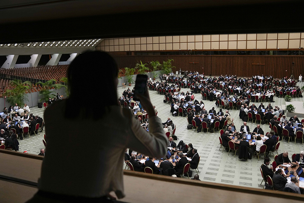 An individual takes a photo of the 16th General Assembly of the Synod of Bishops in the Paul VI Hall at the Vatican, Oct. 9. (AP/Alessandra Tarantino)