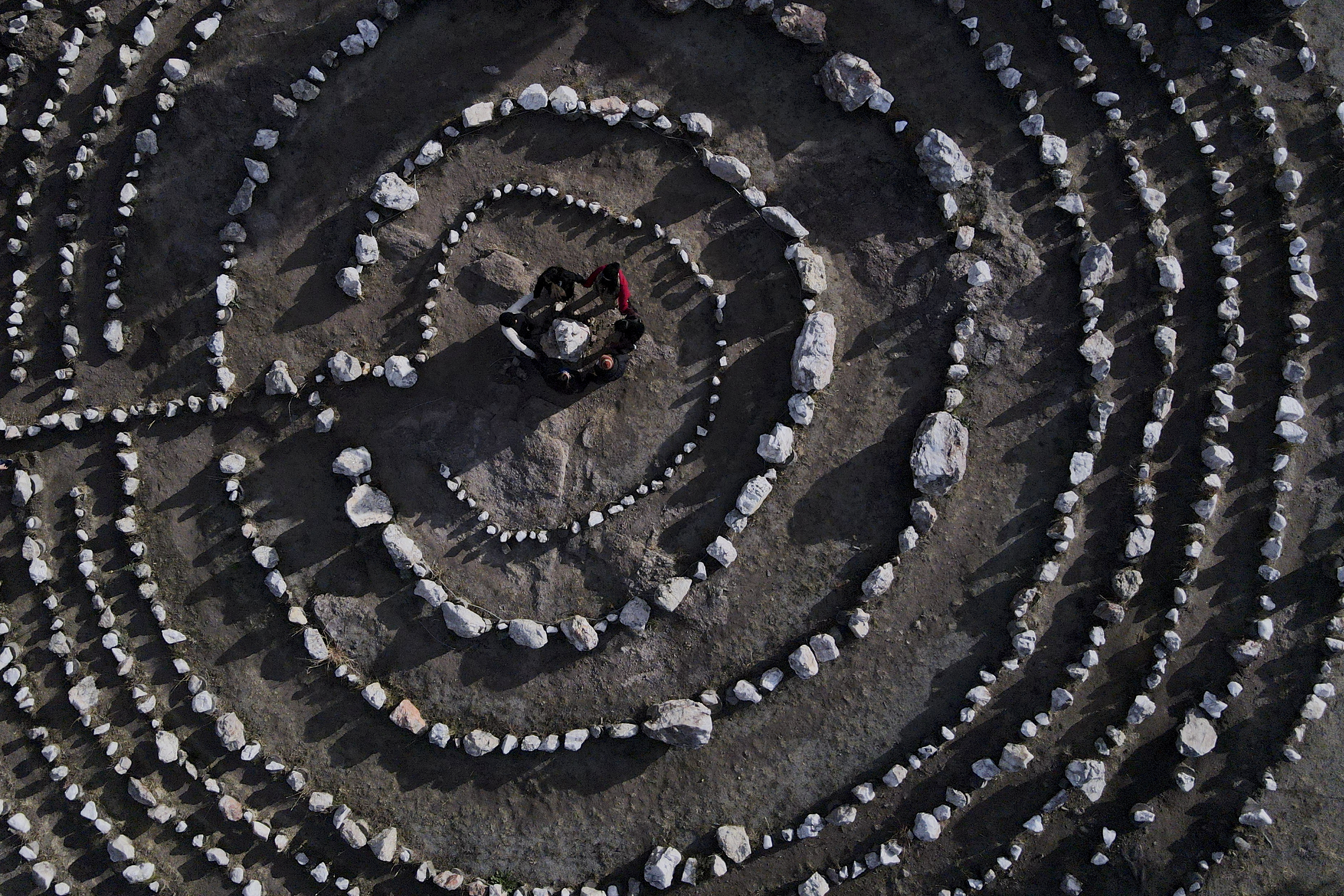 A group of Brazilian tourists hold hands standing in a circle at the heart of a stone labyrinth in the Pueblo Encanto spiritual theme park in Capilla del Monte, Argentina, July 19. (AP/Natacha Pisarenko)