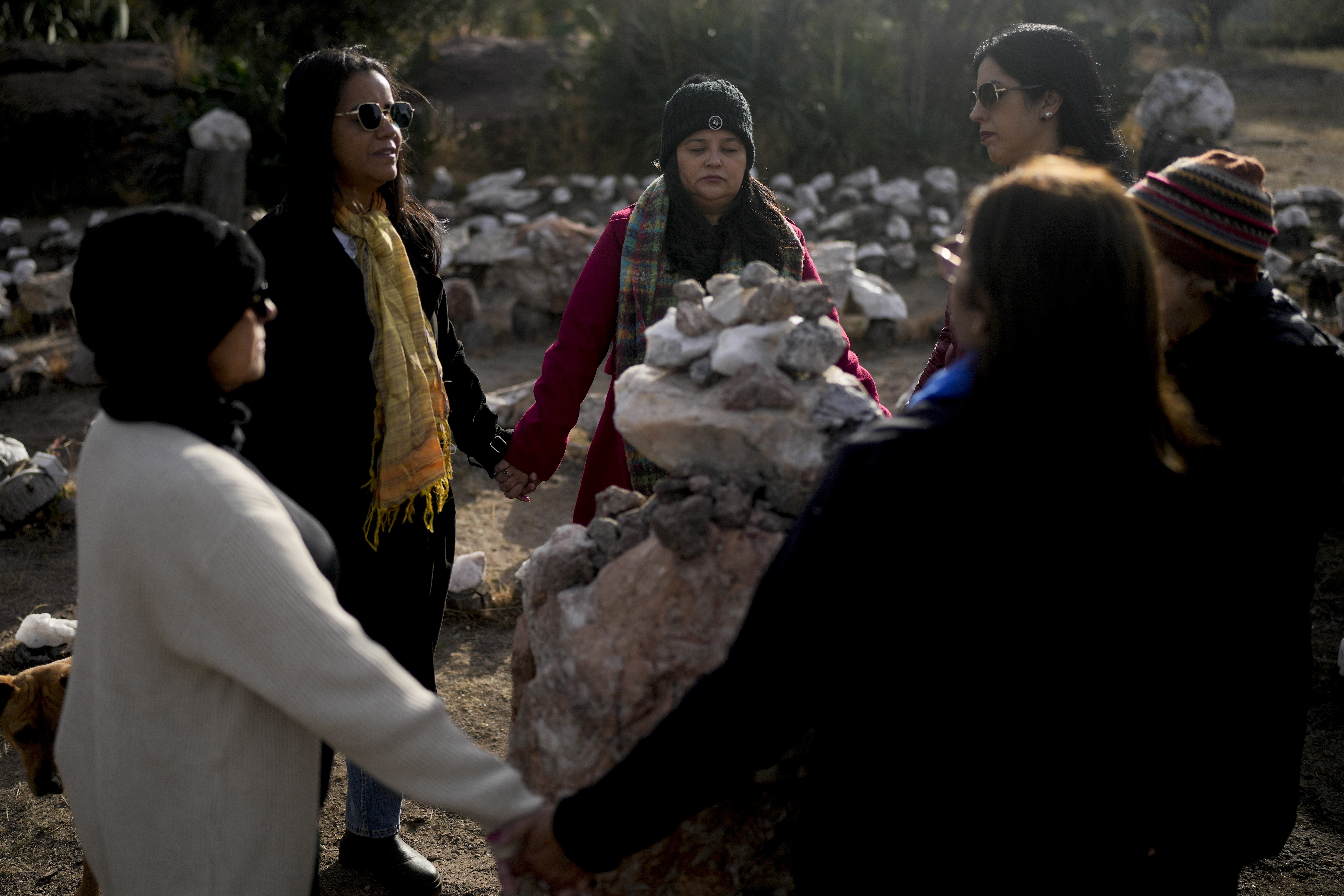 Brazilians Gilma Ribeiro, center, and Neiva Santos, second left, hold hands standing in a circle at the heart of a stone labyrinth in the Pueblo Encanto spiritual theme park in Capilla del Monte, Argentina, July 19. (AP/Natacha Pisarenko)