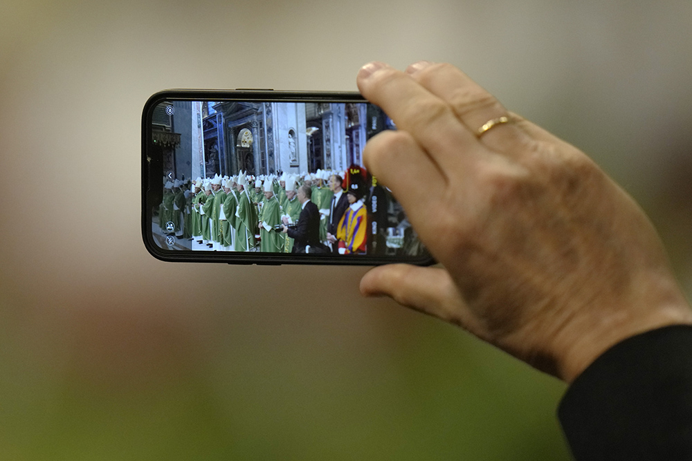A person uses a smartphone to film as Pope Francis presides over a Mass for the closing of the first session of the synod on synodality in St. Peter's Basilica at the Vatican Oct. 29. (AP/Alessandra Tarantino)