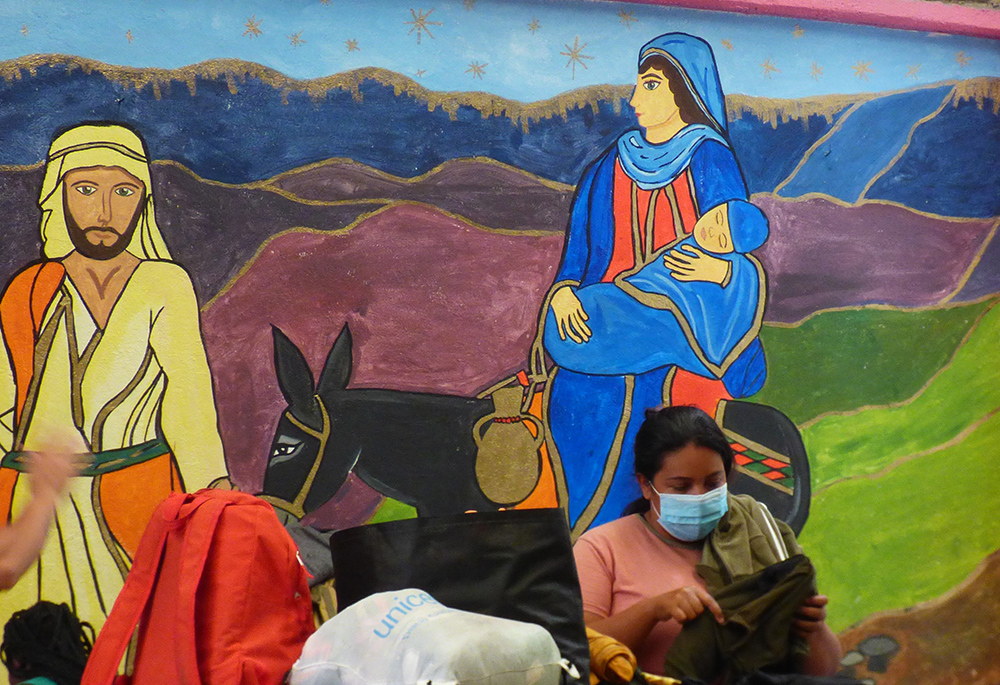 A woman gathers her belongings in front of a mural of Joseph and Mary at the CAFEMIN migrant shelter in Mexico City, Aug. 24. Sr. María Soledad Morales Ríos, one of the Josephine sisters whose congregation operates the shelter, said their charism is to care for the poor, including migrants, the way Joseph and Mary cared for Jesus. (GSR photo/Rhina Guidos) 