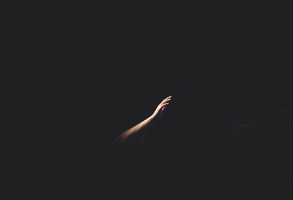 A single hand rises up from amid the darkness in this photo illustration. (Unsplash/Cherry Laithang)