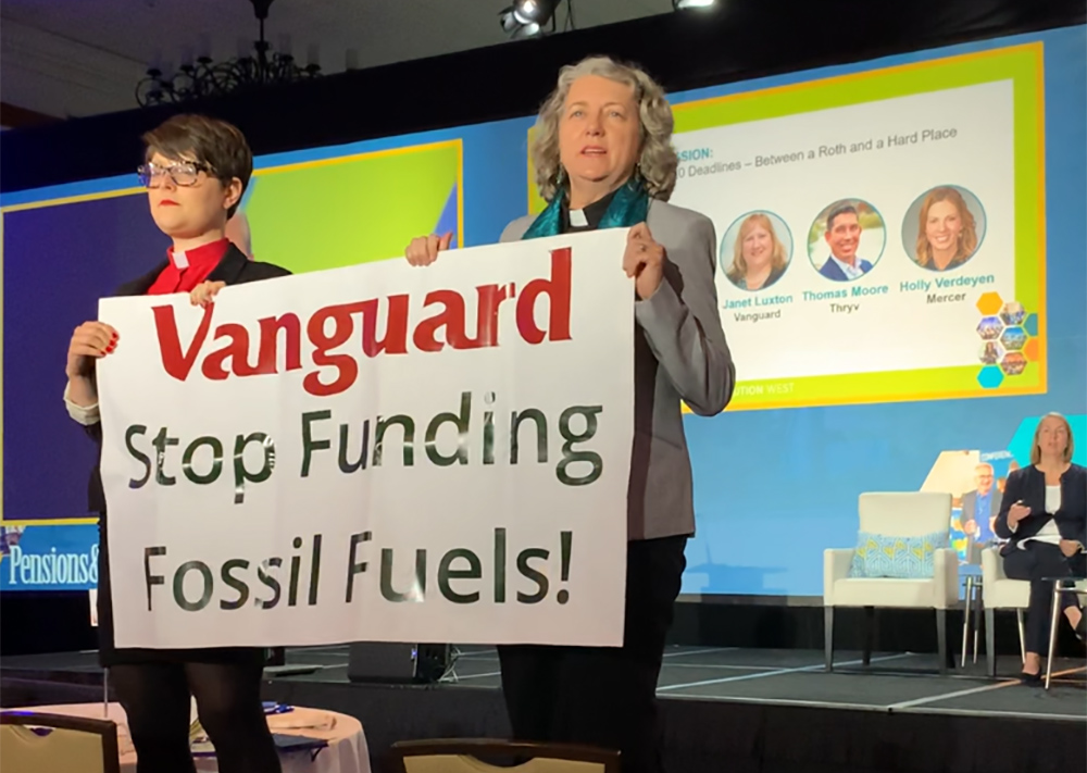 GreenFaith organizers Chelsea MacMillan, left, and Amy Brooks Paradise hold up a banner that reads, "Vanguard Stop Funding Fossil Fuels!" during an Oct. 23 investment industry conference at the Omni La Costa Resort in Carlsbad, California. (Courtesy of GreenFaith)