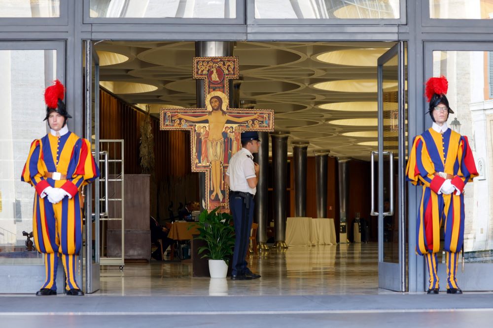 The Swiss Guards stand at the entrance of the Vatican's Paul VI Audience Hall during the assembly of the Synod of Bishops Oct. 6. Synod members were greeted each day by a replica of the San Damiano cross, in front of which St. Francis of Assisi said he heard Jesus tell him to "rebuild my church." (CNS/Lola Gomez)
