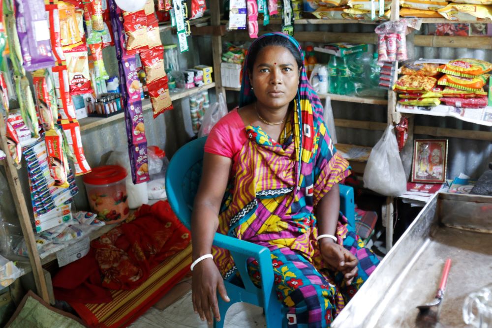 Woman sits inside a small store.