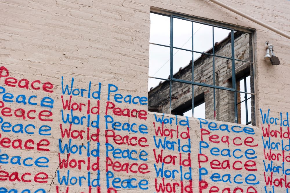 The words "world peace" are written many times on a wall, below a window.