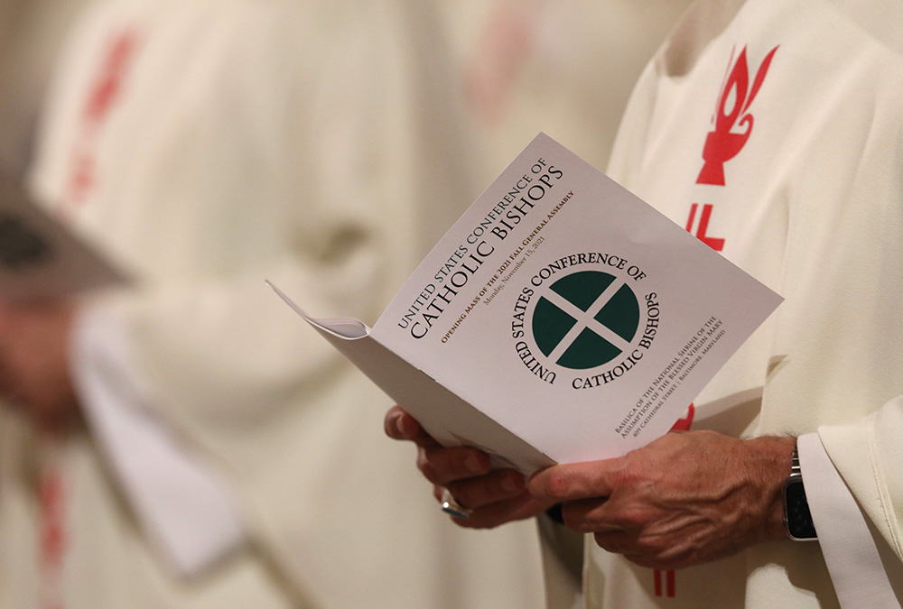A bishop holds a booklet as he attends Mass in a file photo taken during the 2021 fall general assembly of the U.S. Conference of Catholic Bishops. (CNS/Bob Roller)