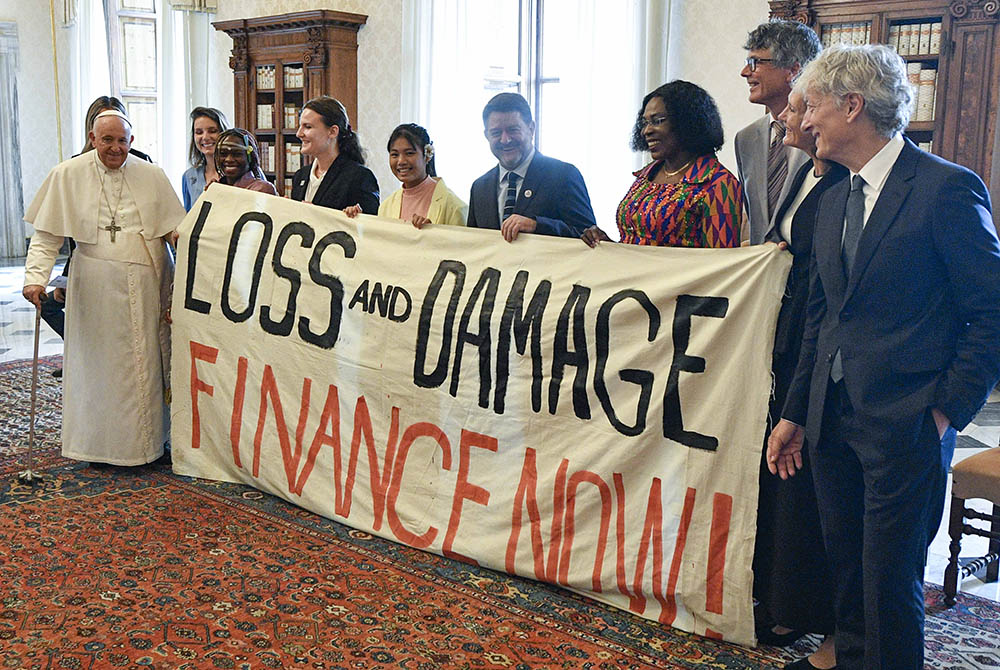 Pope Francis joins others in holding a banner during an audience at the Vatican June 5 with the organizers of the Green & Blue Festival. The banner calls for financing a "loss and damage" fund that was agreed upon at the COP27 U.N. climate conference in 2022. The fund would seek to provide financial assistance to nations most vulnerable and impacted by the effects of climate change. (CNS/Vatican Media)
