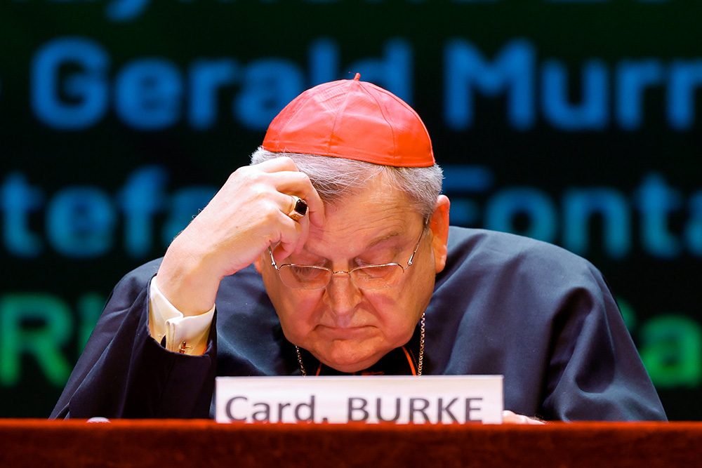U.S. Cardinal Raymond Burke follows the written text of another speaker at the conference "The Synodal Babel" at the Ghione Theater in Rome Oct. 3. (CNS/Lola Gomez)