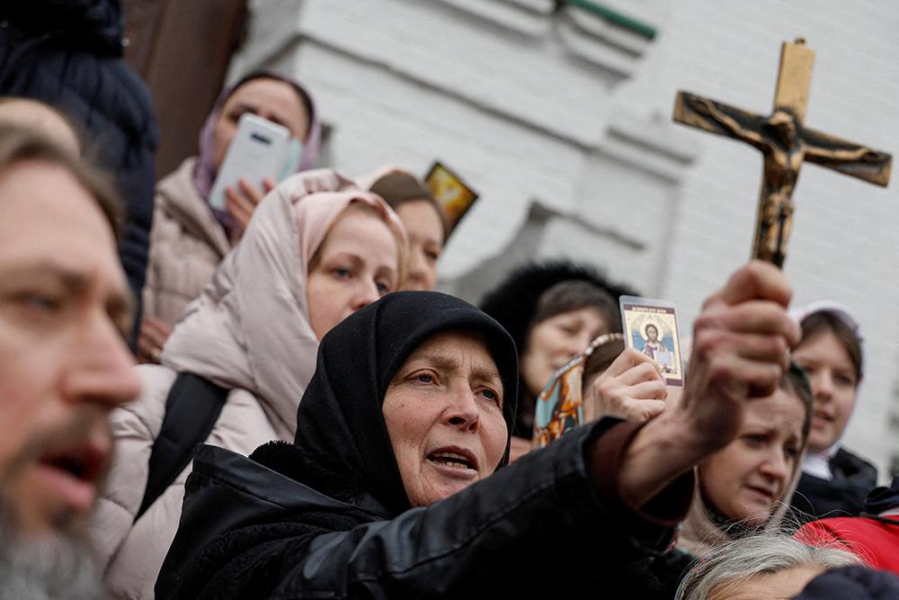 A woman holds a crucifix as others pray while blocking an entrance to a church compound in Kyiv, Ukraine, March 31 amid the Russian invasion. At the U.S. Institute of Peace in Washington Oct. 30, a panel of Ukrainian religious leaders discussed their role in responding to Russia's invasion. (OSV News/Reuters/Valentyn Ogirenko)