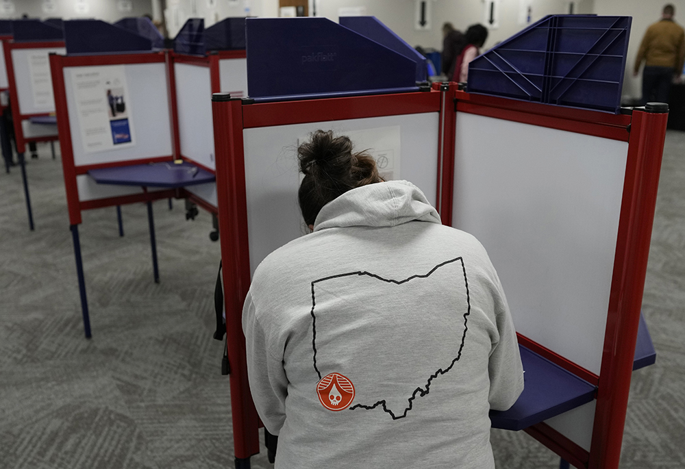 A person with an outline of the state of Ohio on the back of their hoodie fills out a ballot during early in-person voting at the Hamilton County Board of Elections Nov. 2, 2023, in Cincinnati. (AP photo/Carolyn Kaster)