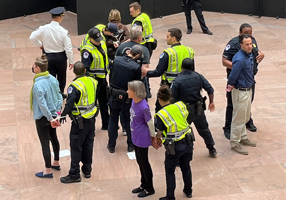 U.S. Capitol Police officers arrest several Catholic activists during a witness inside the Hart Senate Office Building on Nov. 9 to call for an Israel-Hamas cease-fire. At bottom, in purple, is Jean Stokan, justice coordinator for immigration and nonviolence for the Sisters of Mercy of the Americas. At right, in a blue shirt, is Eli McCarthy, just peace fellow for the Franciscan Action Network. (NCR photo/Joshua J. McElwee)