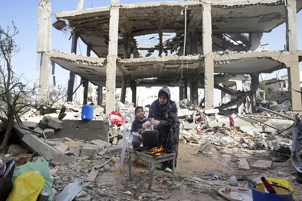 Palestinian woman Hiyam Qudih cooks in front of her family's building destroyed in the Israeli bombardment of the Gaza Strip in the village of Khuza'a Nov. 26, on the third day of a temporary ceasefire between Hamas and Israel. (AP/Adel Hana)