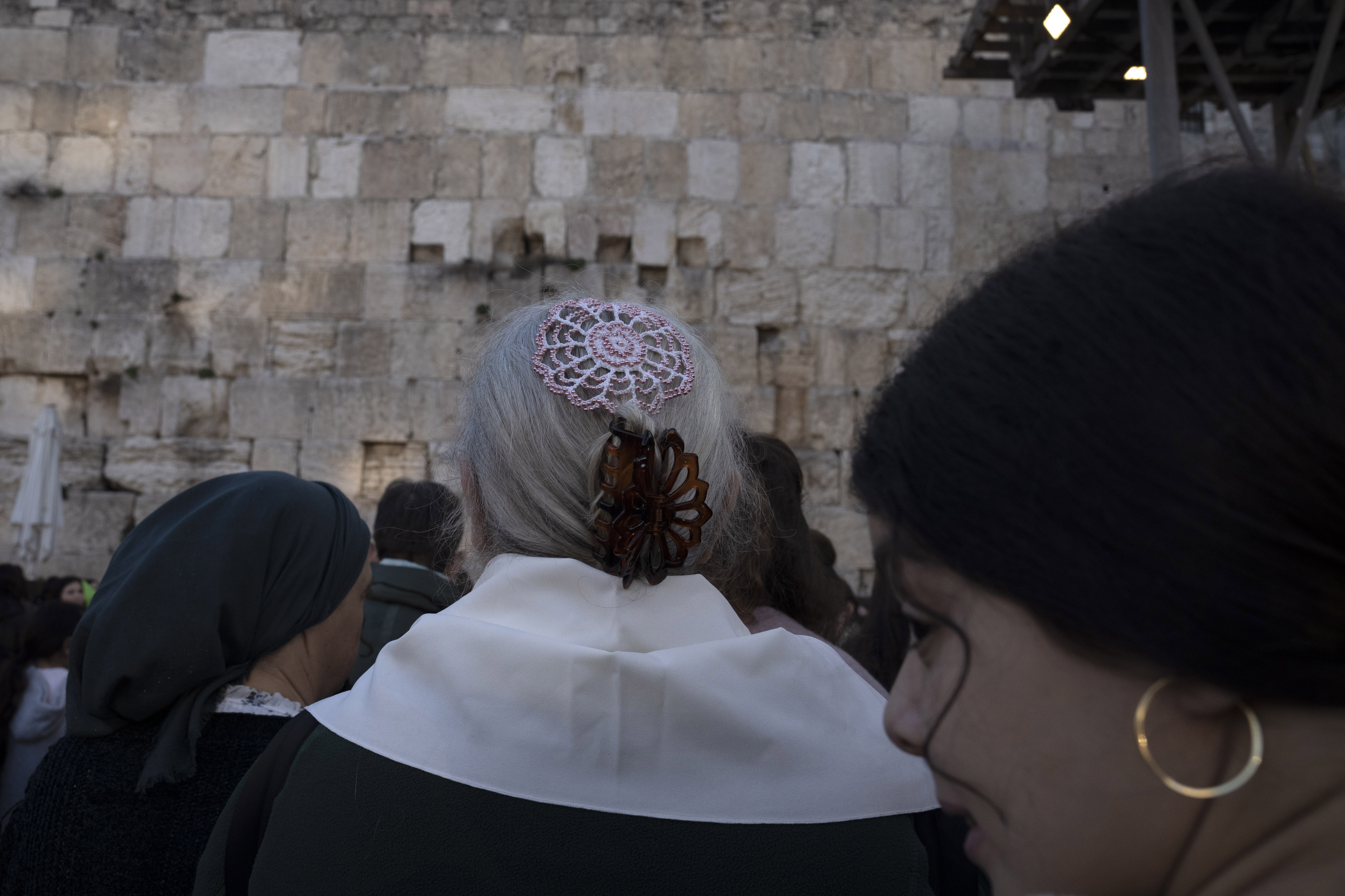 In the photo, a member of Women of the Wall, positioned at the center, dons a headscarf during the Rosh Hodesh prayer, marking the new month. The prayer takes place at the Western Wall, the holiest site where Jews can pray, in Jerusalem's Old City on Monday, Jan. 23, 2023. The Women of the Wall group has been engaged in a decadeslong campaign for gender equality at the holy site and now faces new challenges under Israel's right-wing government. (AP photo/Maya Alleruzzo)