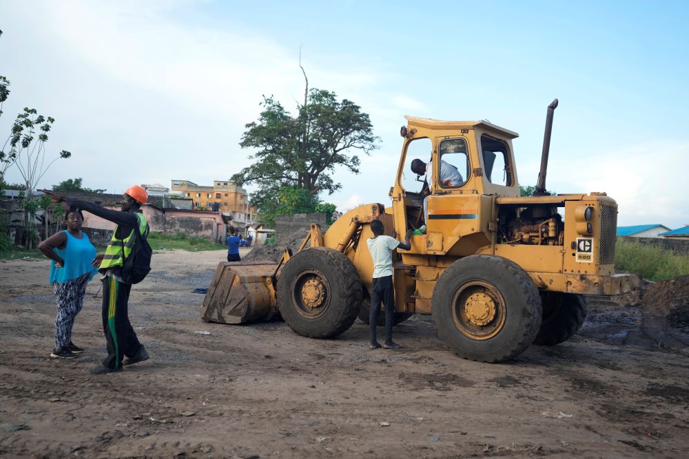 Construction workers work near the last remaining sacred tree of the Odjou Ekoun Oro forest in the village of Houeyogbe, Benin, near Port Novo, on Wednesday, Oct. 4, 2023. Between 2001 and 2012 approximately 45% of Benin’s sacred forests had disappeared or were diminished, according to the Circle for Safeguarding of Natural Resources. (AP/Sunday Alamba)