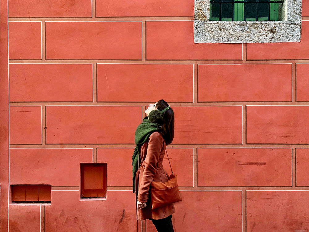 A young woman standing in profile in front of a wall, looking up (Unsplash/Jennifer Griffin)
