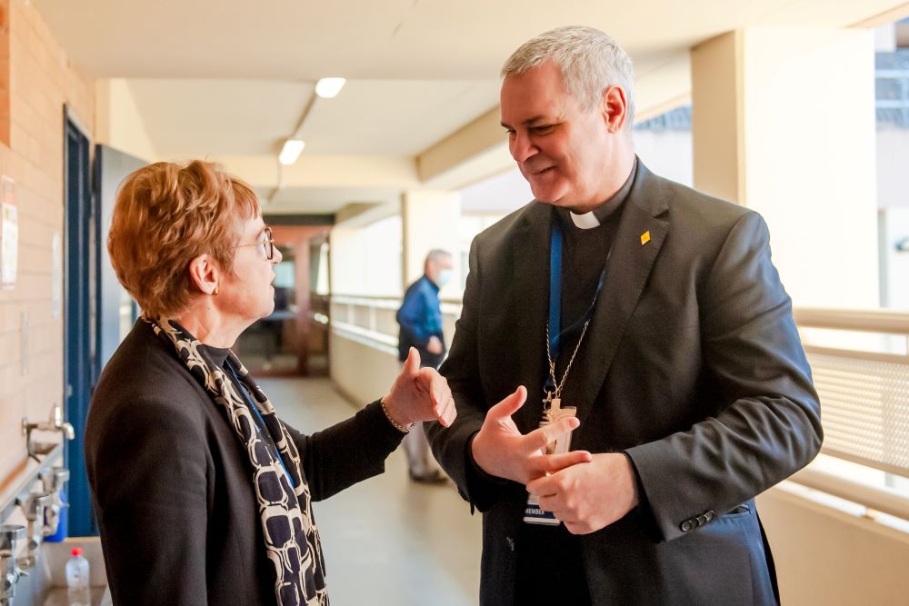 Bishop talks with a woman outside a meeting.