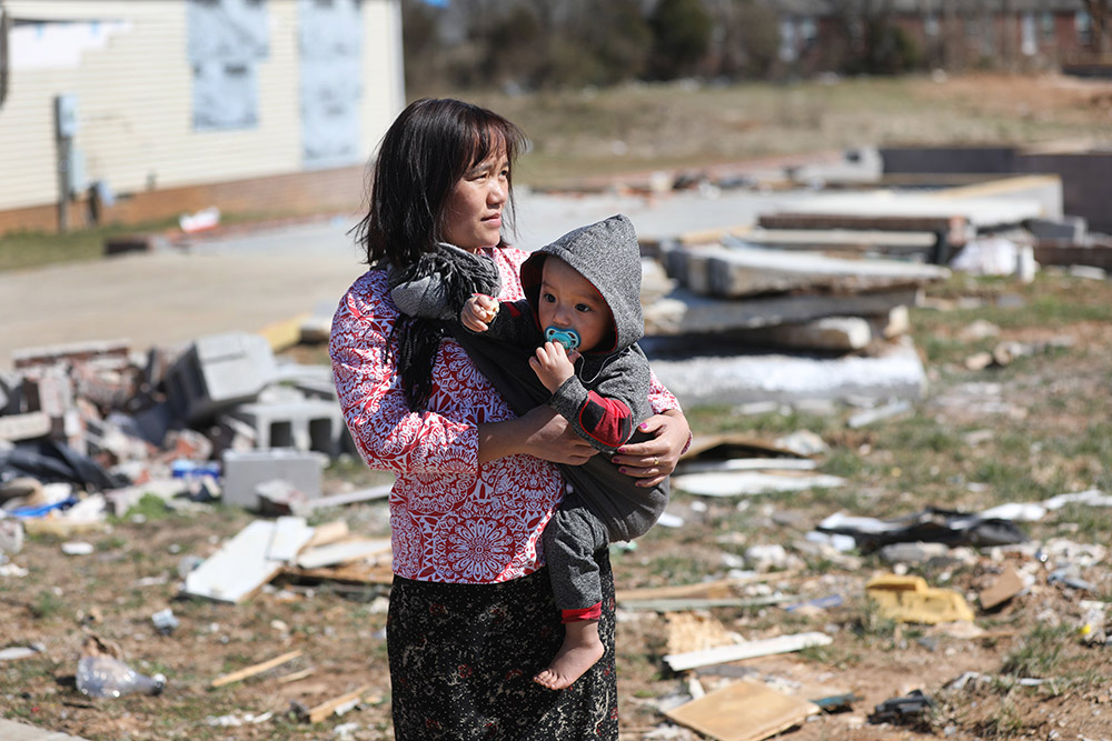 Margaret Myu Mang, a Myanmar Catholic, holds her child, Nicholas, 1, near their damaged home Bowling Green, Kentucky, March 3, 2022, weeks after a tornado ripped through the town. (CNS/Bob Roller)