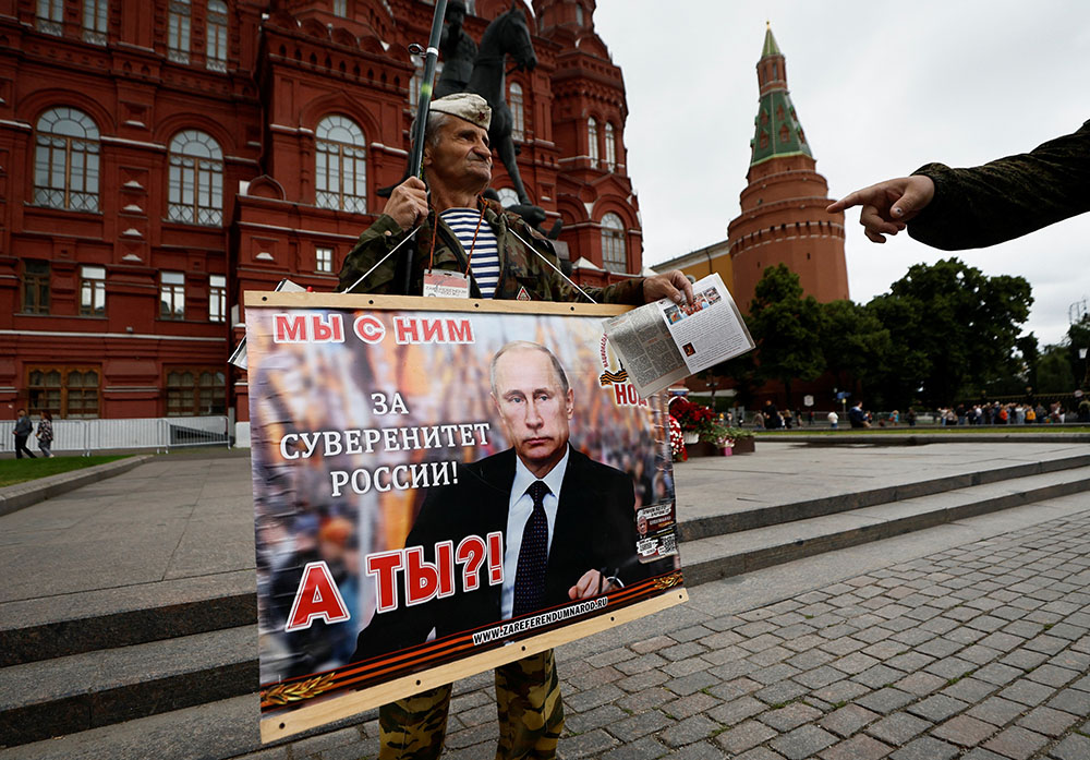 A man holds a placard in support of Russian President Vladimir Putin as a tower of the Kremlin is seen in the background in Moscow June 24. (OSV News/Reuters/Maxim Shemetov)