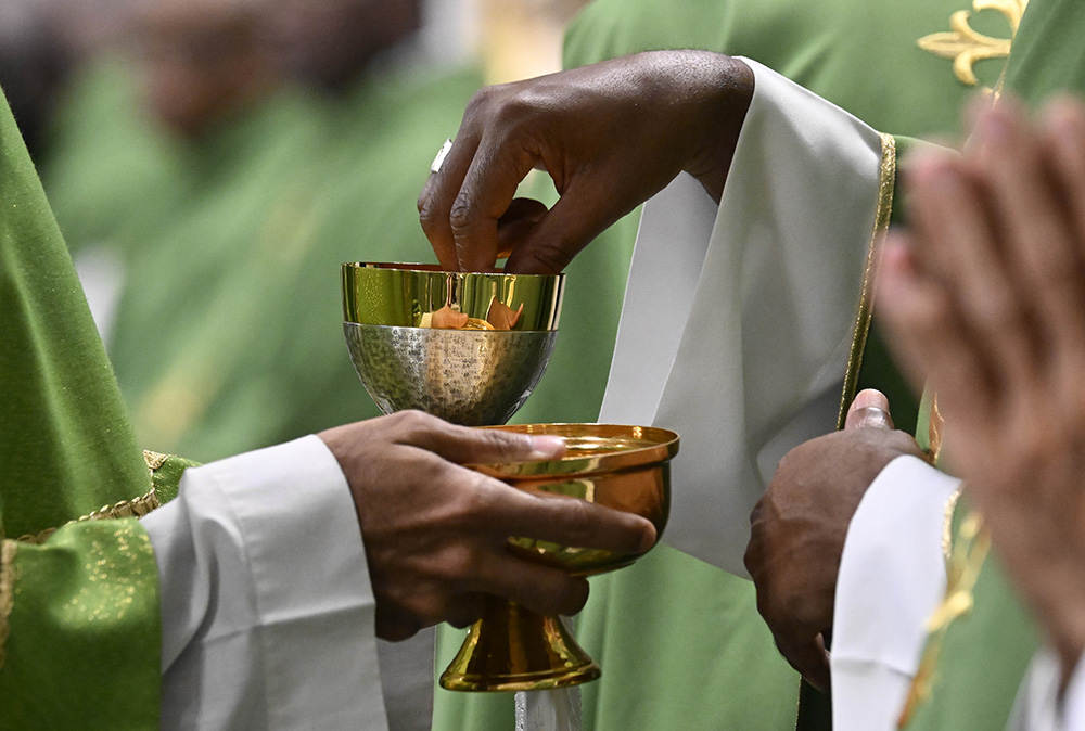 A concelebrating priest dips the host into consecrated wine during Mass in St. Peter's Basilica at the Vatican Oct. 29, marking the conclusion of the first session of the Synod of Bishops on synodality. (CNS/Vatican Media)