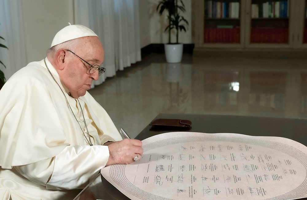 Pope Francis signs the Interfaith Statement on Climate Change in his Vatican residence Dec. 3. (CNS/Vatican Media)