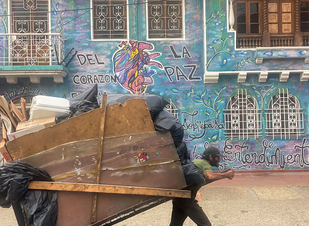 Un hombre transporta material para reciclaje recolectado cerca de un mural con el texto 'Del corazón emana la paz', en Bogotá, Colombia, el 22 de noviembre de 2023. Aunque los acuerdos de paz de 2016 oficialmente pusieron fin al conflicto de décadas entre las FARC y el Gobierno, los más pobres, muchos de ellos en comunidades rurales, todavía sufren violencia, dijo la hermana Diana Herrera Castañeda. (Foto: GSR/Rhina Guidos)