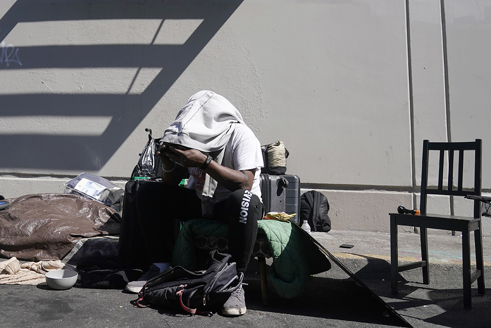 Maurice Palmer waits with his possessions as a homeless encampment is removed in San Francisco Aug. 29, 2023. Homeless people and their advocates say crackdowns on tent encampments are cruel and costly, and there aren't enough homes or beds for everyone. (AP/Jeff Chiu)