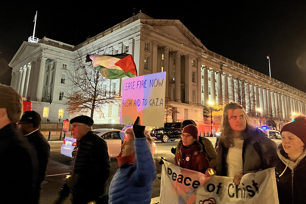 Christian protesters hold a ceasefire sign, Pax Christi USA banner and a Palestinian flag as they pass the U.S. Department of the Treasury in Washington, D.C., Dec. 11. (NCR photo/Aleja Hertzler-McCain)