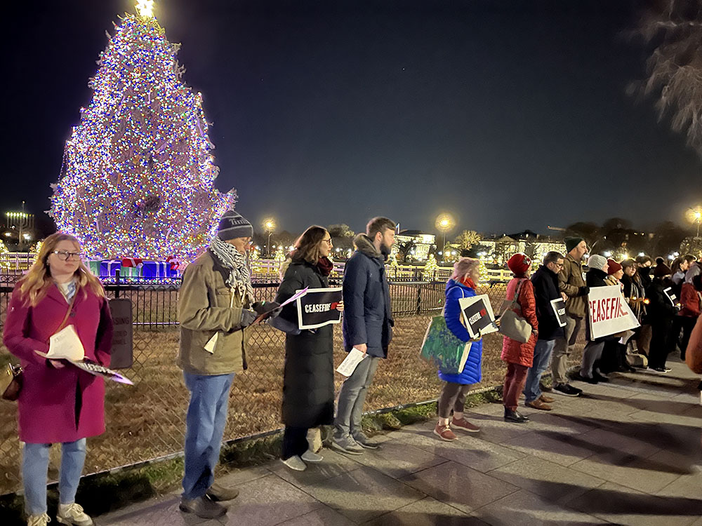 Christian protesters hold ceasefire signs while standing between the National Christmas Tree and the White House in Washington, D.C., Dec. 11. (NCR photo/Aleja Hertzler-McCain)