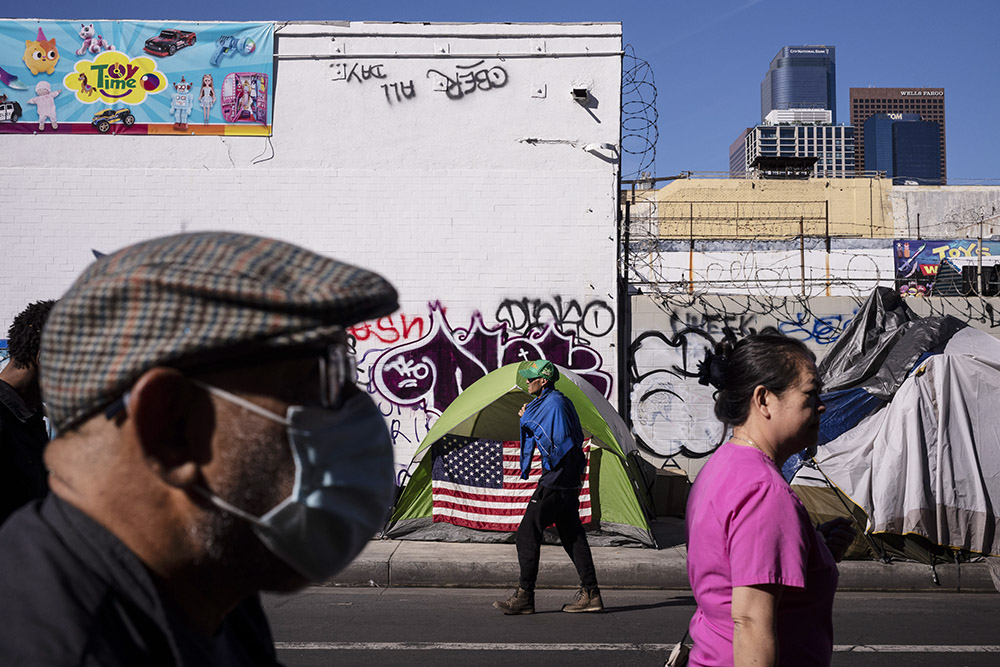 Pedestrians pass by a homeless tent adorned with an American flag across the street from the Los Angeles Mission in the Skid Row area of downtown Los Angeles Nov. 22, 2023. (AP/Jae C. Hong)