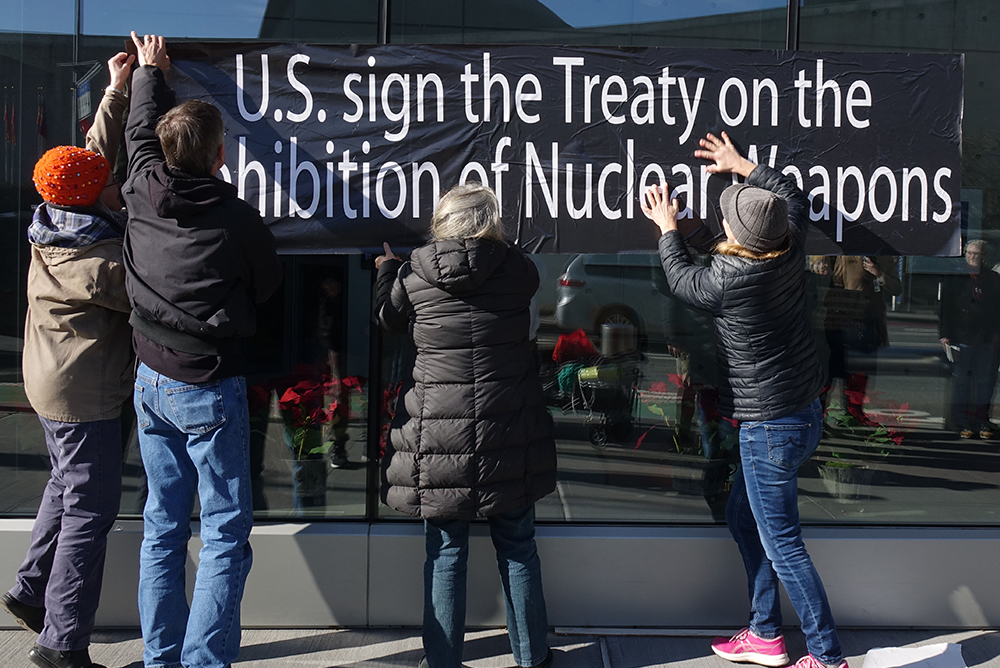 A group of Catholic activists place large sticker posters on the walls of the United States Mission to the United Nations in New York City on Nov. 30, which read "US Sign the Treaty on the Prohibition of Nuclear Weapons." (Felton Davis)