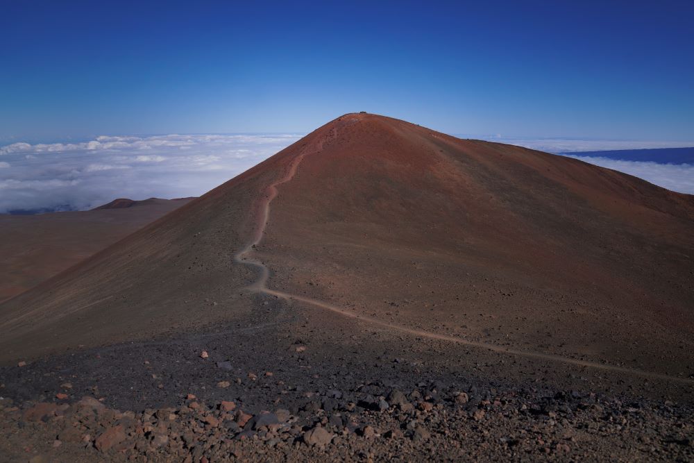 A foot trail leads to an "ahu," or ceremonial platform atop Pu'u Wekiu, an important summit to many Native Hawaiian cultural practitioners, on the sacred mountain Mauna Kea in Hawaii on Saturday July, 15, 2023. Along the slopes of this sacred mountain are ceremonial platforms, ancestral burial sites, and an alpine lake whose waters are believed to have healing properties. (AP/Jessie Wardarski)