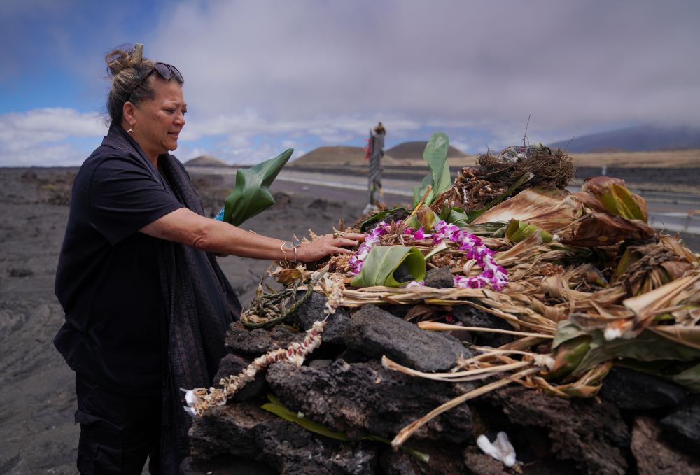 Kealoha Pisciotta, a cultural practitioner and longtime activist, lays offerings before praying at an "ahu," or ceremonial platform, part of the way up Mauna Kea in Hawaii, on Saturday, July 15, 2023. Along the slopes of this sacred mountain are ceremonial platforms, ancestral burial sites, and an alpine lake whose waters are believed to have healing properties. (AP/Jessie Wardarski)