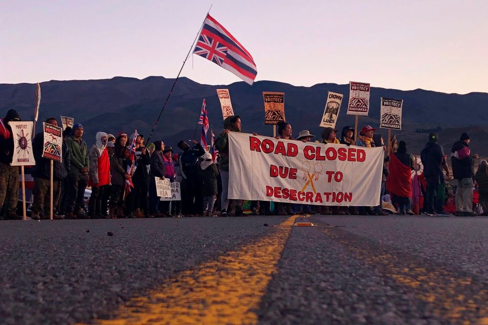 Demonstrators gather to block a road part of the way up Hawaii's tallest mountain, Monday, July 15, 2019, in Mauna Kea, Hawaii, to protest the construction of a giant telescope on land that some Native Hawaiians consider sacred. After the 2019 protest against a proposed Thirty Meter Telescope near the summit, the state of Hawaii passed a law, which gives both scientists and spiritual practitioners a say in the future of the mountain. This has led to small steps toward new dialogue.(AP/Caleb Jones)