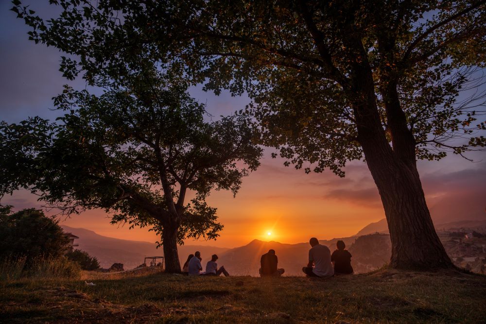 People sit and reflect as the sun sets over the scenic Kadisha Valley, a holy landmark for Lebanon's Maronite Christians, in the northeast mountain town of Bcharre, Lebanon, Friday, July 21, 2023. 